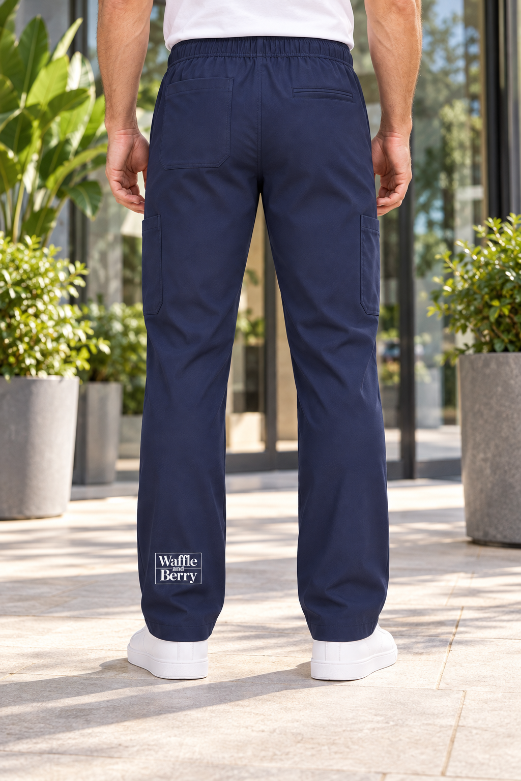 Photo-reference-based AI-edited mockup of Navy cargo pants from the rear, showing the white Waffle and Berry box print near the lower rear left hem. Not a physical sample photograph.