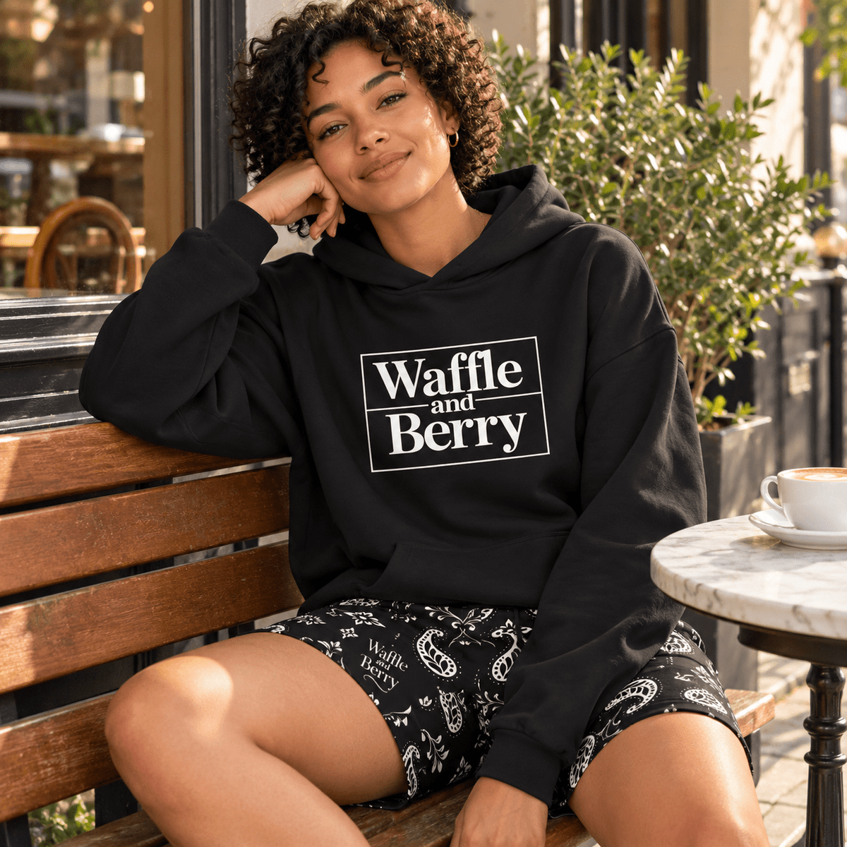 Model wearing Waffle and Berry Hoodie and paisley shorts, seated