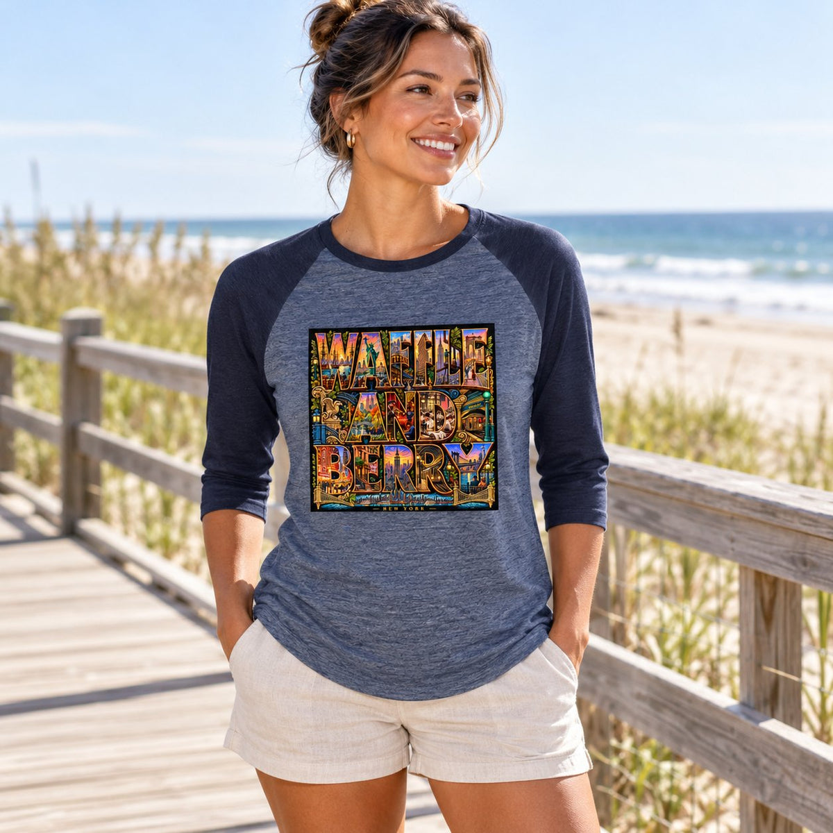 Illustrative model wearing the Heather Denim/Navy New York Wins raglan shirt on a sunny beach boardwalk, front view.