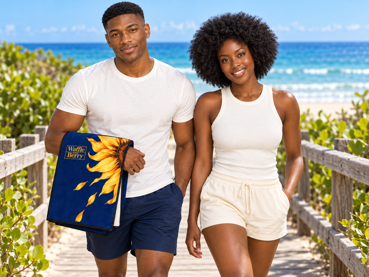 AI lifestyle illustration: Marcus and Simone on a boardwalk holding the folded Sunflower Beach Day Towel, showing its navy sunflower face and white cotton reverse.